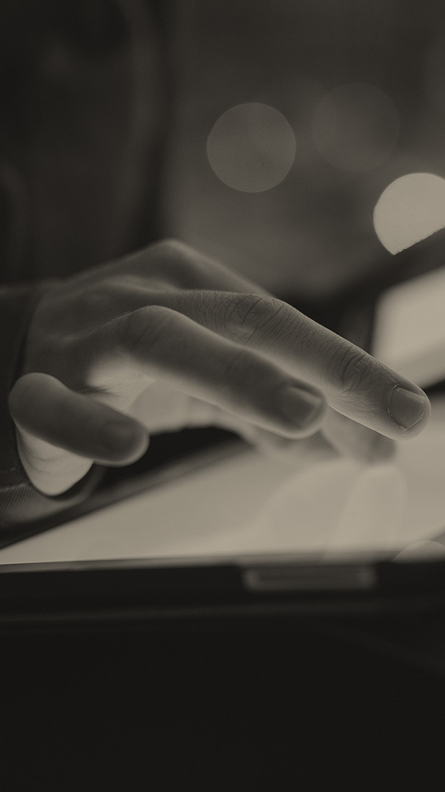 A hand illuminated by a tablet screen as it interacts with it.